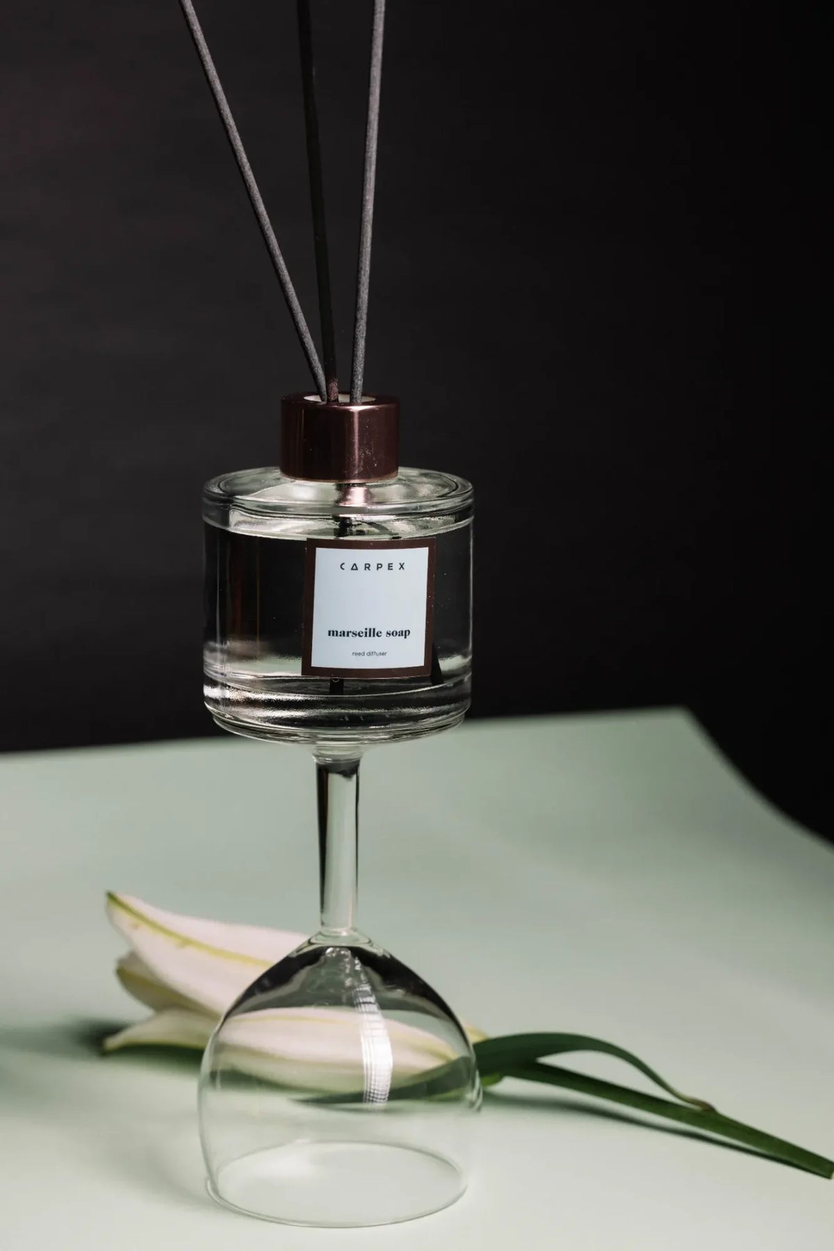 Carpex “Marseille Soap” reed diffuser, ters şarap kadehi üzerinde modern kontrastlar içinde sergilenmiş. Pentome Studio’da çekilmiştir.
Carpex “Marseille Soap” reed diffuser elegantly displayed upside down on a wine glass with minimalist contrast. Photographed at Pentome Studio.