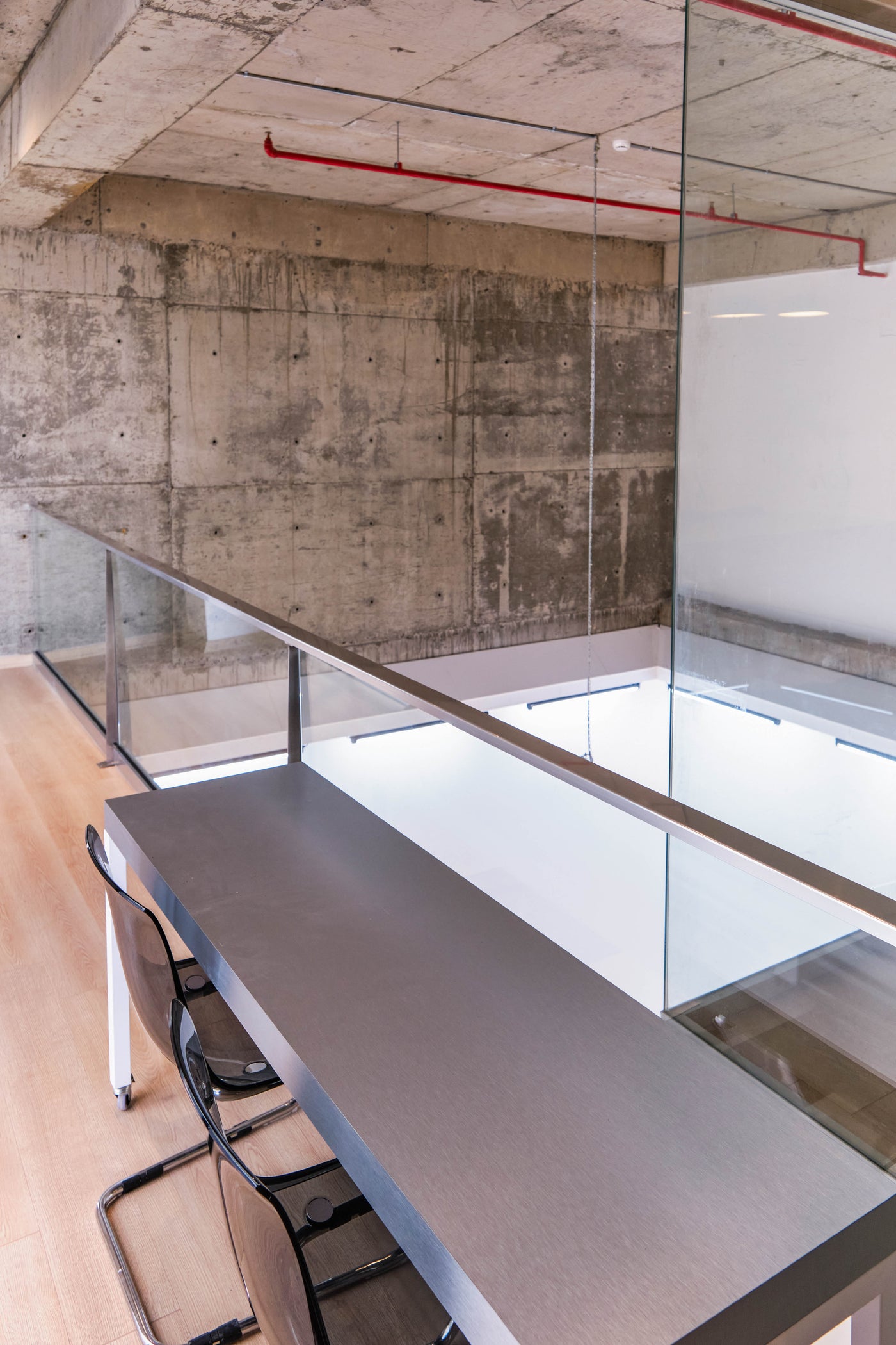 Pentome Studio’nun üst katta yer alan çalışma alanı, beton duvarlar ve cam korkuluklarla minimalist bir tasarım sunar. Pentome Studio’da çekilmiştir.
The mezzanine workspace at Pentome Studio features a minimalist design with concrete walls and glass railings. Photographed at Pentome Studio.